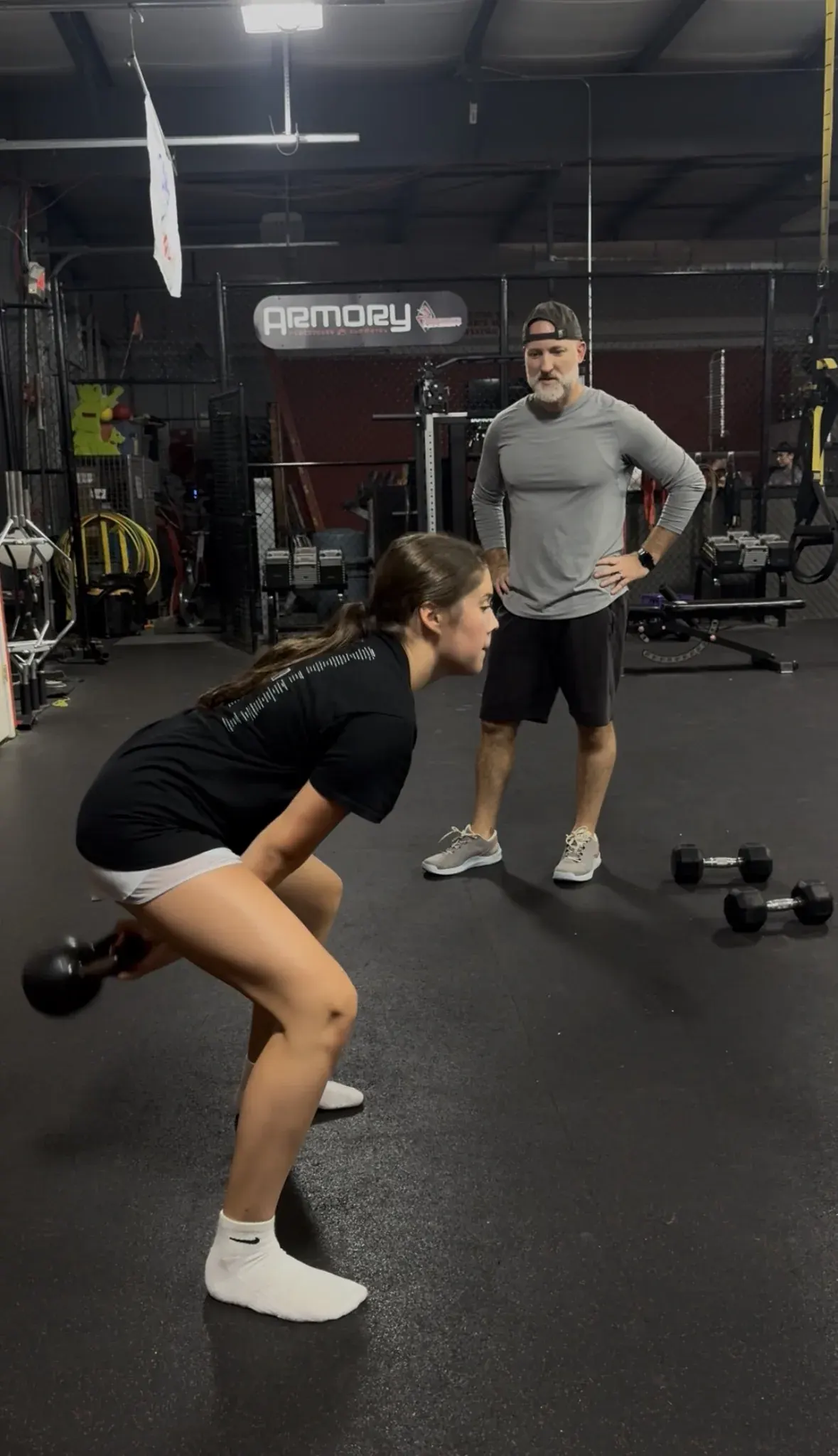 Coach Aaron watching an athlete swing a kettlebell